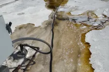 Thumbnail for Rusty pipes and a black cable on a dirty white rooftop with large brown water stains and patches.