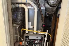 Thumbnail for Residential HVAC furnace system with ductwork and PVC piping inside a utility closet.