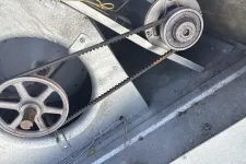 Thumbnail for Close-up of an industrial fan belt connected to pulleys inside a metal HVAC unit.