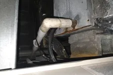 Thumbnail for Close-up of rusted HVAC duct with connected white PVC pipe and black cables in a basement or utility area