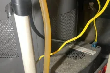 Thumbnail for Smyrna AC Cooling Repair in Atlanta 30080 by The Air Company of GA.  Close-up of a red pump connected to pipes with yellow wires and a yellow DeWalt power tool on a concrete floor.