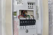 Thumbnail for Close-up of wiring terminals inside a thermostat with labeled connectors and colored wires attached