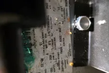 Thumbnail for Close-up of a compressor specification label showing voltage, pressure, and power ratings with slight rust and dirt.