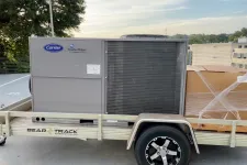Thumbnail for Carrier WeatherMaker HVAC unit on Bear Track aluminum trailer parked outdoors near trees and buildings.