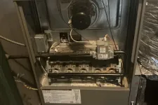 Thumbnail for Open furnace showing internal components including burners, ignitor, and ventilation duct in a basement setting.