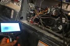 Thumbnail for Residential AC Cooling Repair in Atlanta 30327 by The Air Company of GA.  Hand holding inspection camera in front of an open HVAC furnace with wires and components exposed.