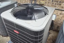 Thumbnail for Outdoor HVAC air conditioning unit with a large top fan and metal casing next to a brick wall.