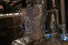 Thumbnail for Insulated HVAC ductwork wrapped in reflective material inside a dimly lit basement crawlspace.