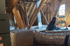 Thumbnail for View of attic showing HVAC ductwork, wooden beams, insulation, and a child's toy near a window.