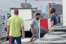 Thumbnail for Technicians inspecting and working on rooftop air conditioning units in an urban setting with buildings in the background.