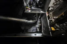 Thumbnail for Interior view of an open furnace with metal ductwork and wiring inside a dimly lit basement space.