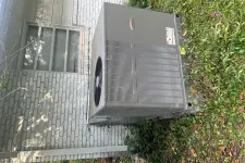 Thumbnail for Outdoor Lennox air conditioning unit installed next to a white brick house with grass and plants nearby.