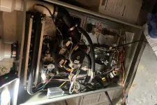 Thumbnail for Open furnace unit with visible wiring, circuit boards, pipes, and mechanical components inside a utility space.
