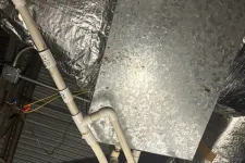 Thumbnail for PVC pipes and insulated ductwork connected to a galvanized metal HVAC unit in an industrial ceiling space.
