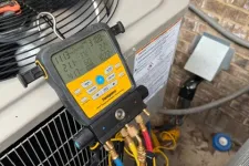 Thumbnail for Digital manifold gauge connected to an outdoor HVAC unit with colored hoses and tools nearby.