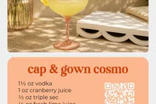 Thumbnail for Cap & Gown Cosmo cocktail in a glass with lemon garnish and floral decor on a sunny table.