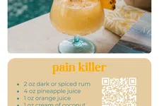 Thumbnail for Pain Killer cocktail with pineapple wedge and orange slice garnish by a poolside setting with a book.