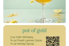 Thumbnail for Elegant Pot of Gold cocktail in etched coupe glass garnished with lemon twist and edible gold flakes on mint background.