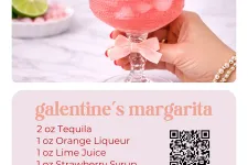 Thumbnail for Pink Galentine's margarita in a sugar-rimmed glass garnished with lime and strawberry held by a hand with bracelet.