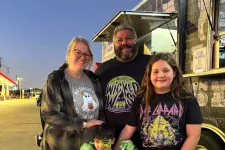 Thumbnail for Family of four in casual and costume attire posing near a food truck at dusk outdoors.