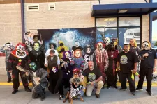 Thumbnail for Group of people and a dog in spooky Halloween costumes posing outside a building with a full moon backdrop.