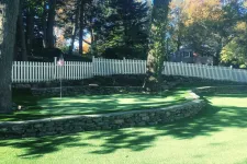 Thumbnail for a stone wall with a fence and trees in the background