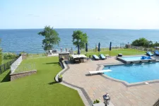 Thumbnail for a pool with a deck and chairs by it and a body of water in the background