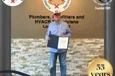 Thumbnail for Senior man holding award certificate at Plumbers Local Union 72 office celebrating 55 years of service.