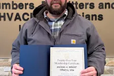 Thumbnail for Man holding certificate in front of Plumbers, Pipefitters and Service Technicians union sign on wall