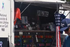 Thumbnail for Mobile suicide prevention booth with YouMatter and hotline info, a man walking nearby under blue sky