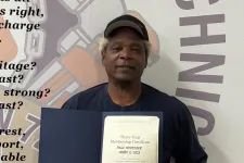 Thumbnail for Man holding a thirty-year union membership certificate standing in front of a wall with union-related text and logo.