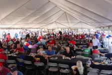 Thumbnail for a large crowd of people sitting at tables in a tent