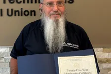 Thumbnail for Man with long beard holding a certificate in front of Plumbers, Pipefitters & HVACR Technicians Local Union 72 sign.