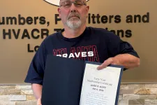 Thumbnail for Man wearing a cap and glasses holding a certificate and key standing by a union service technicians logo and text.