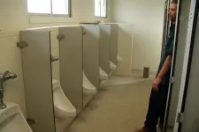 Thumbnail for a person standing next to urinals