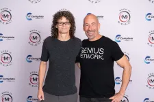 Thumbnail for Two smiling adults posing in front of a branded backdrop with logos and slogans for IT Complete and TMT Keep It Real