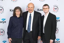 Thumbnail for Three professionally dressed individuals posing at a media event with branded backdrop logos.