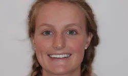 Thumbnail control image for Smiling young woman with braided blonde hair and blue eyes wearing pearl earrings against a plain background