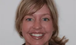 Thumbnail control image for Close-up portrait of a smiling blonde woman with blue eyes against a plain background.