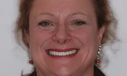 Thumbnail control image for Close-up of a smiling woman with curly hair, wearing earrings and a brown top against a plain background