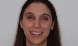 Thumbnail control image for Smiling woman with long brown hair and light brown eyes against plain gray background