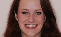 Thumbnail control image for Close-up portrait of a smiling woman with long brown hair against a plain background