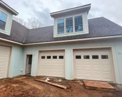 a house with garages and a dirt yard