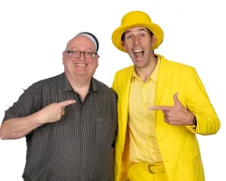 Two men smiling and pointing at each other, one wearing all yellow with a hat, the other in a dark striped shirt.