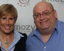 Smiling woman and man standing together in front of a Mozy by EMC branded backdrop at an event.