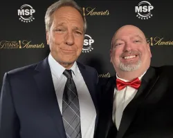 Two men in formal attire smiling at the MSP Titans of the Industry Awards event backdrop.