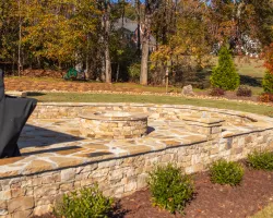 a stone patio with a stone wall and a stone wall with a stone circle and trees and a