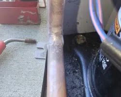 Close-up of a copper pipe showing soldering joint near HVAC components and colored electrical wires.