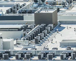 Rooftop with multiple HVAC air conditioning units installed on a flat white building roof under clear sky.