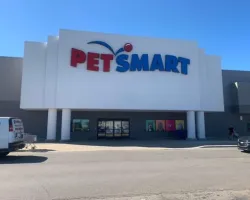 PetSmart storefront with large red and blue logo on white facade under clear blue sky.